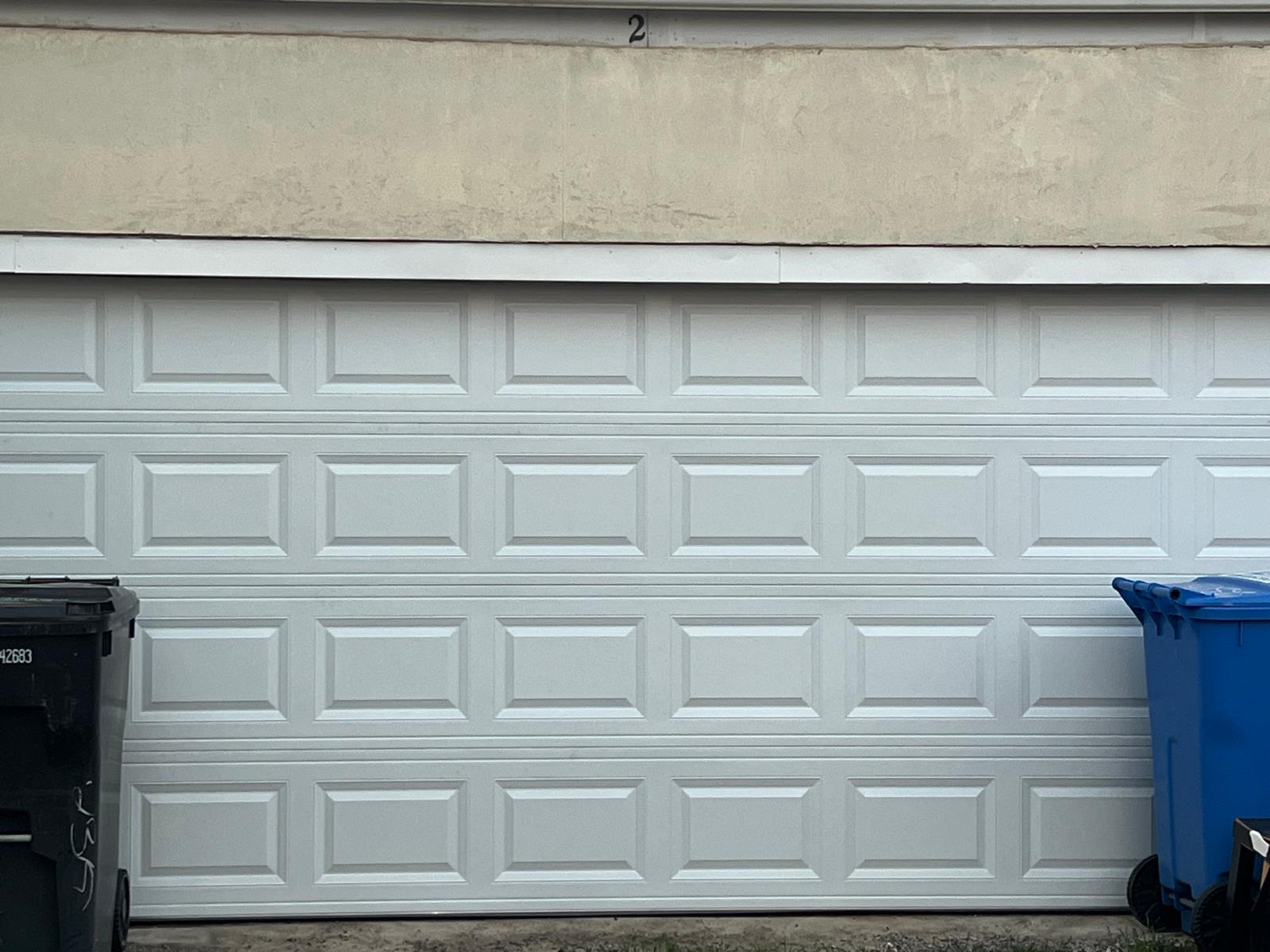 Close exterior view of the newly installed white raised-panel garage door