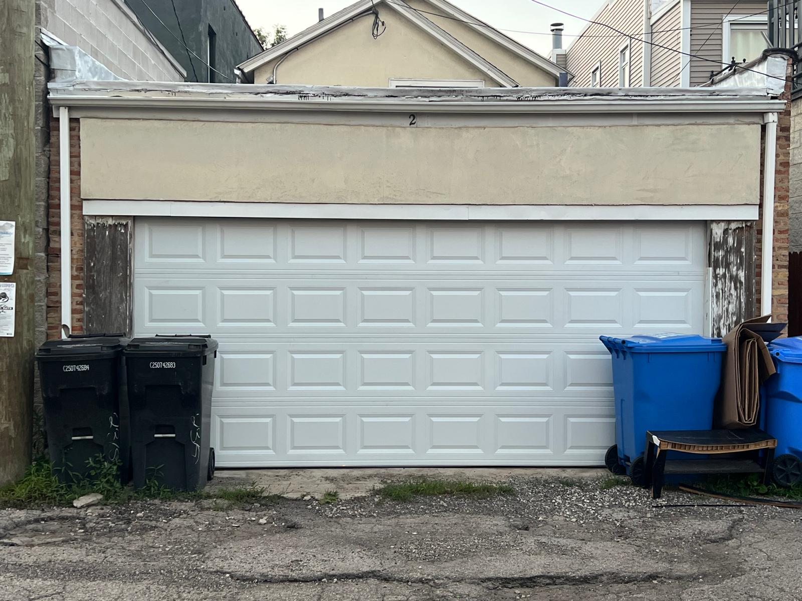 Completed white double garage door installation viewed from the alley