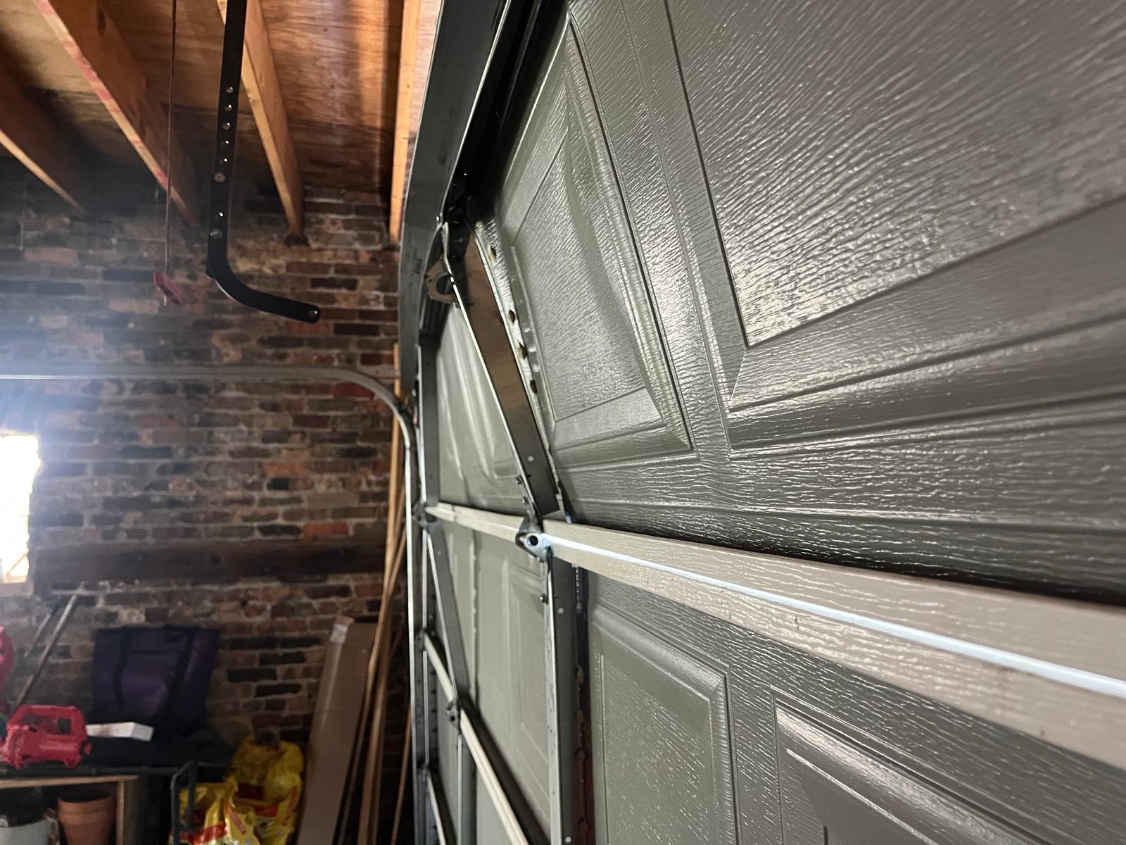 Close-up of garage door panel, hinge, and track hardware